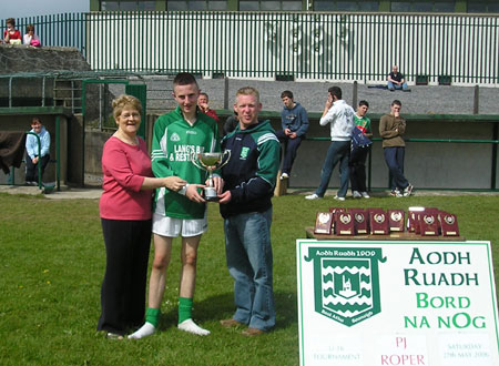 Mary Roper (left) and Brian Roper (right) present the PJ Roper trophy to James Brennan, the captain to the victorious Grange team, after the final of the PJ Roper under 16 tournament in Ballyshannon last Saturday.