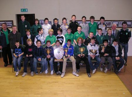 The County Championship winning under 12 squad pictured with mentors Jim Kane and Gerry McIntyre and county stars Brian Roper and Niall McCready. The trophies pictured are the County Champion's trophy, The O'Donnell League Plaque, The Gerry Quinn Memorial Cup won at Derrylaughan in Tyrone, The Southern Division trophy, The Willie Rogers trophy and the Jim McLaughlin Memorial Cup won at Saint Theresa's in Belfast.