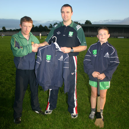 Packy McGrath of McGrath's Bouncy Castles presenting a set of track suits for the Aodh Ruadh under 12 hurlers to their manager, Peter Horan. Also present is the team's captain, Eugene Drummond.
